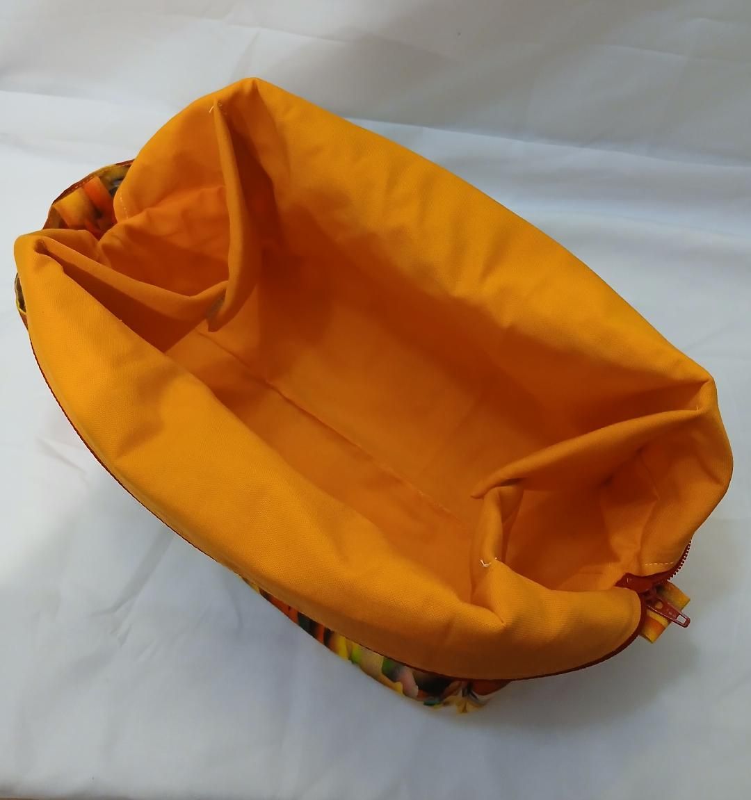 Orange tote bag with black-and-white striped lining, viewed from above on a white surface