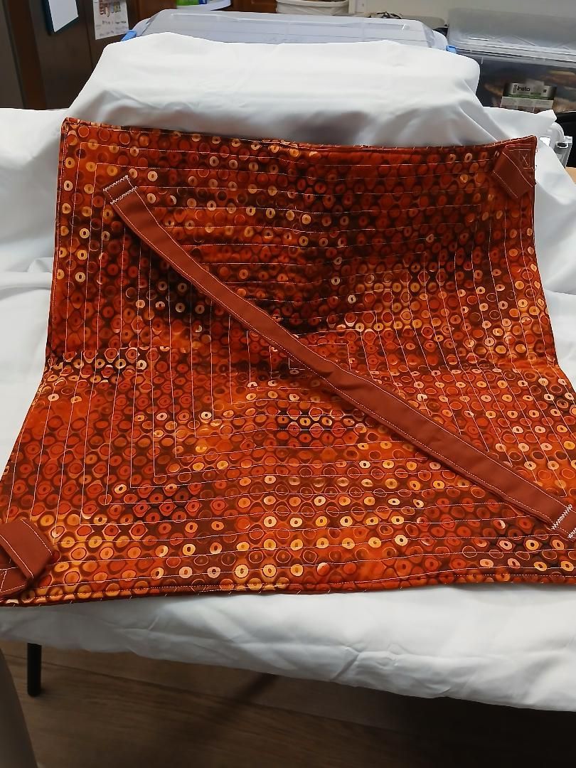 Orange patterned fabric draped over a white cushioned seat on a chair in a room