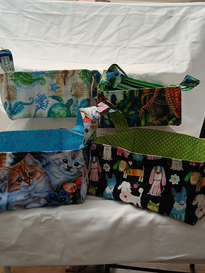Four colorful handmade fabric bags with animal and floral prints arranged on a white couch.