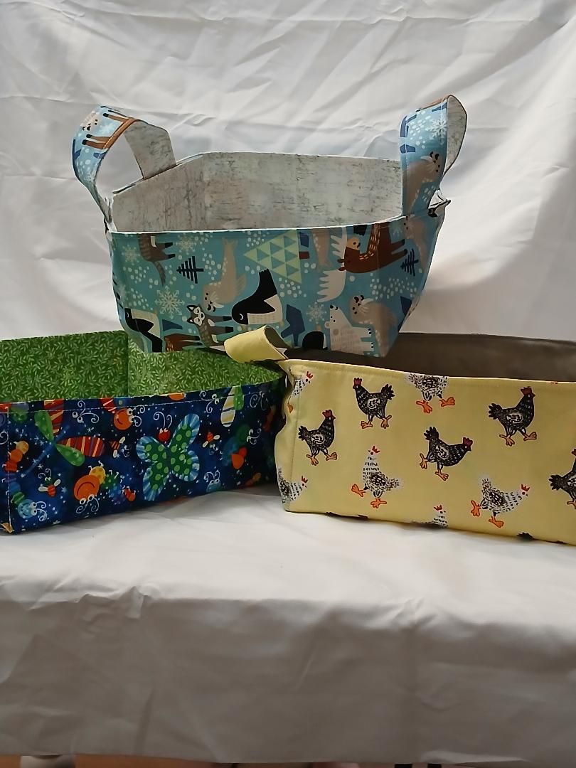 Colorful handmade fabric bags and pouches displayed on a white tablecloth.