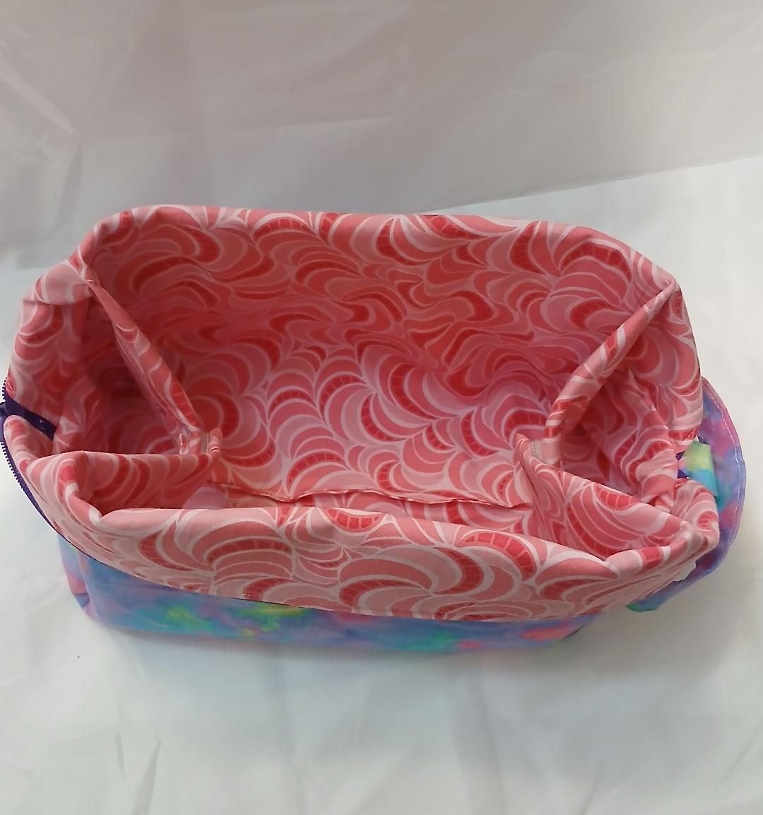 Pink patterned fabric basket with colorful trim on a white background
