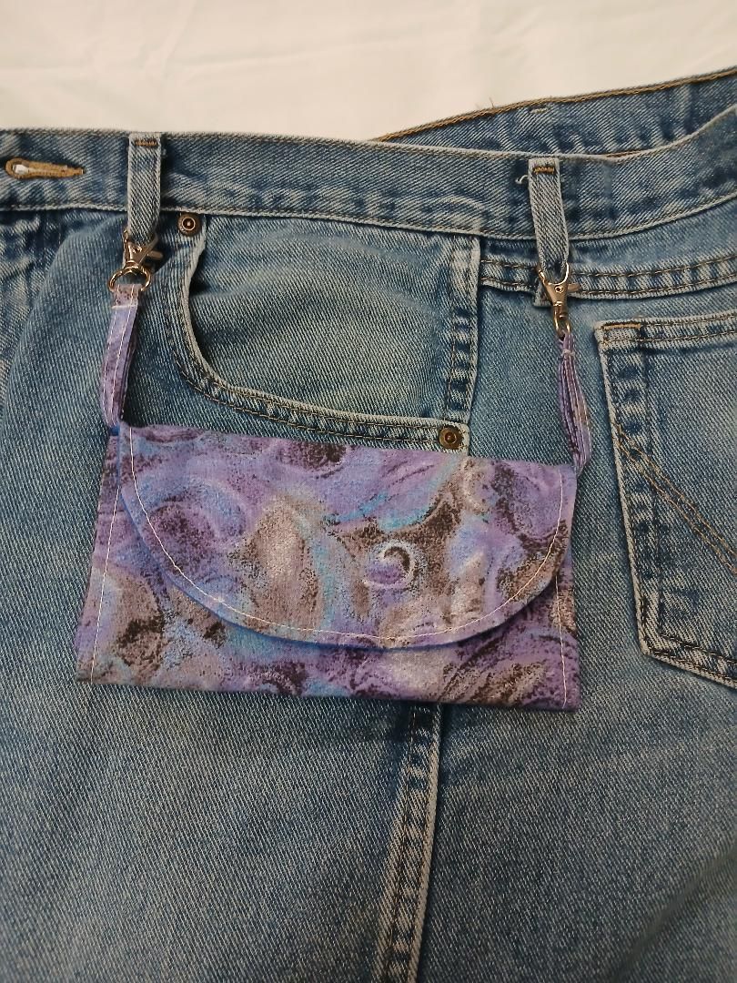 Back of blue jeans with a purple patch pocket stitched onto the waistband area