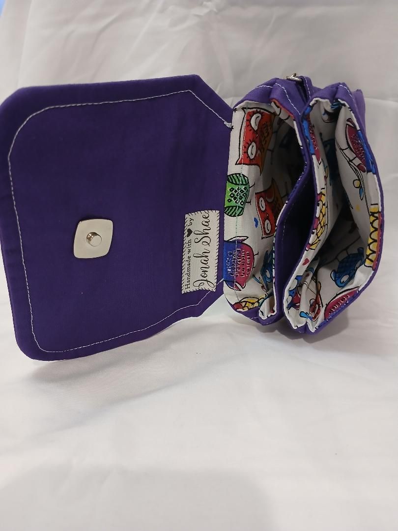 Purple zippered pouch opened to show patterned lining and a small white clasp on a white background