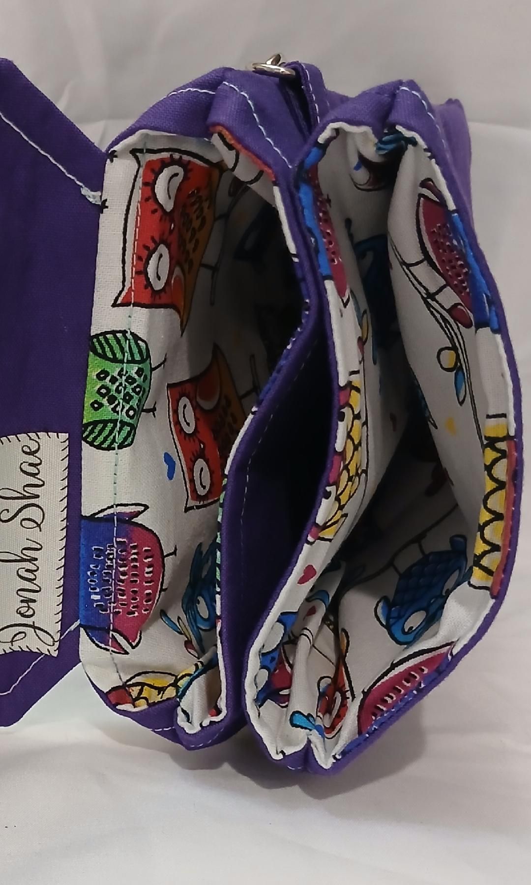 Purple handmade fabric pouch with colorful patterned lining, open to show two compartments