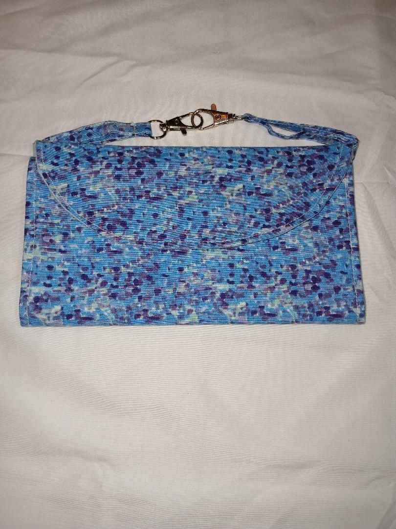 Blue patterned scarf with a brown strap laid flat on a white bedspread