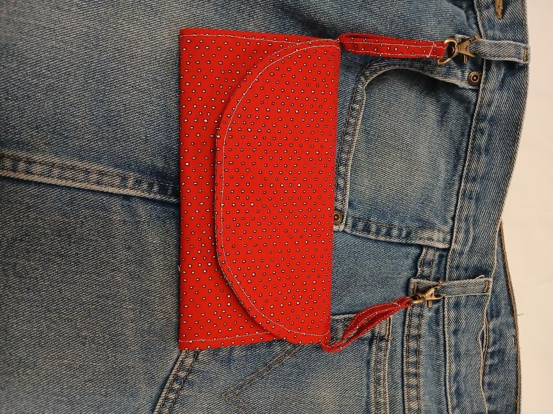 Red patterned pocket on blue denim jeans with a flap and side strap detail