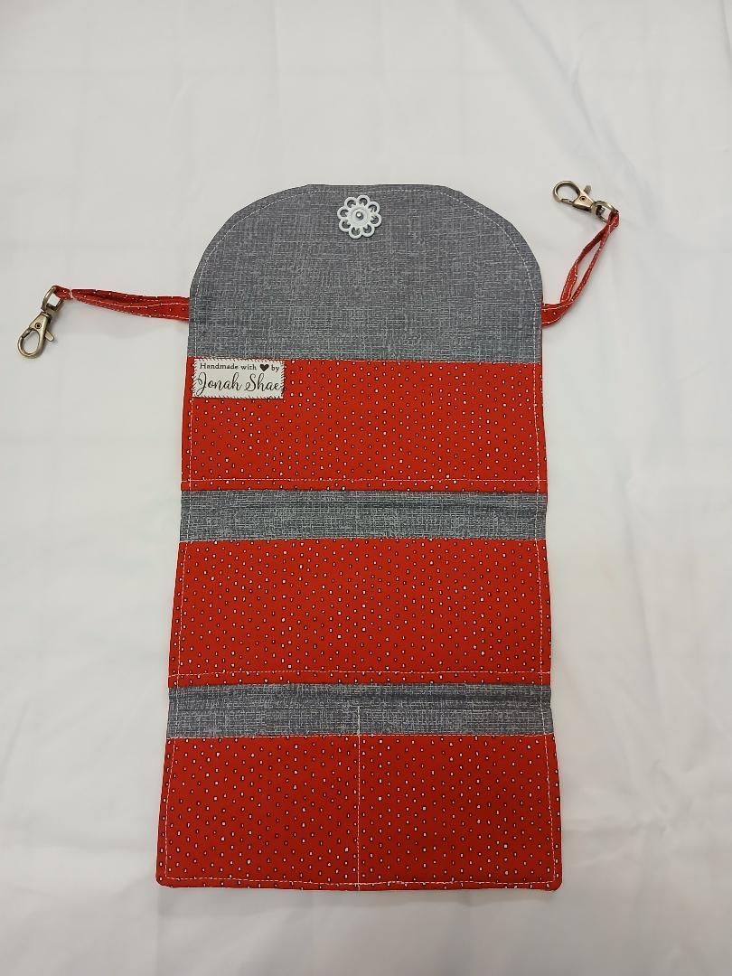 Red and gray woven hanging pouch with a strap and clasp on a white background