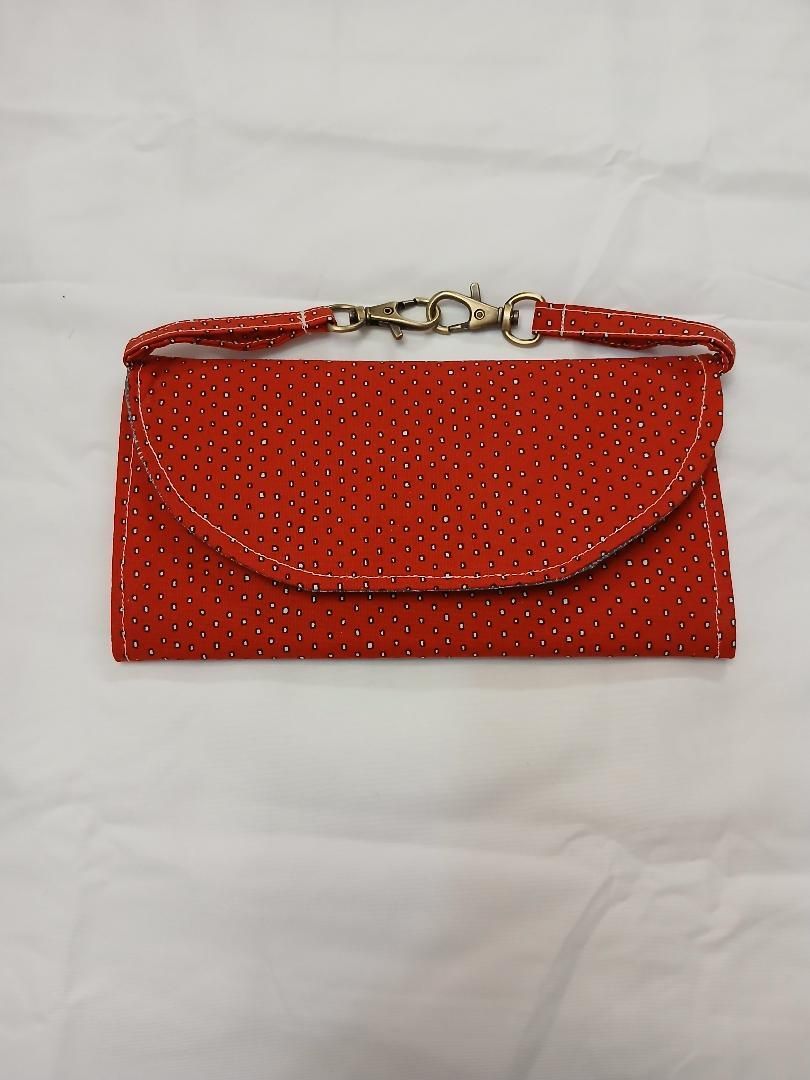 Red beaded clutch purse with gold clasp and strap on a white background