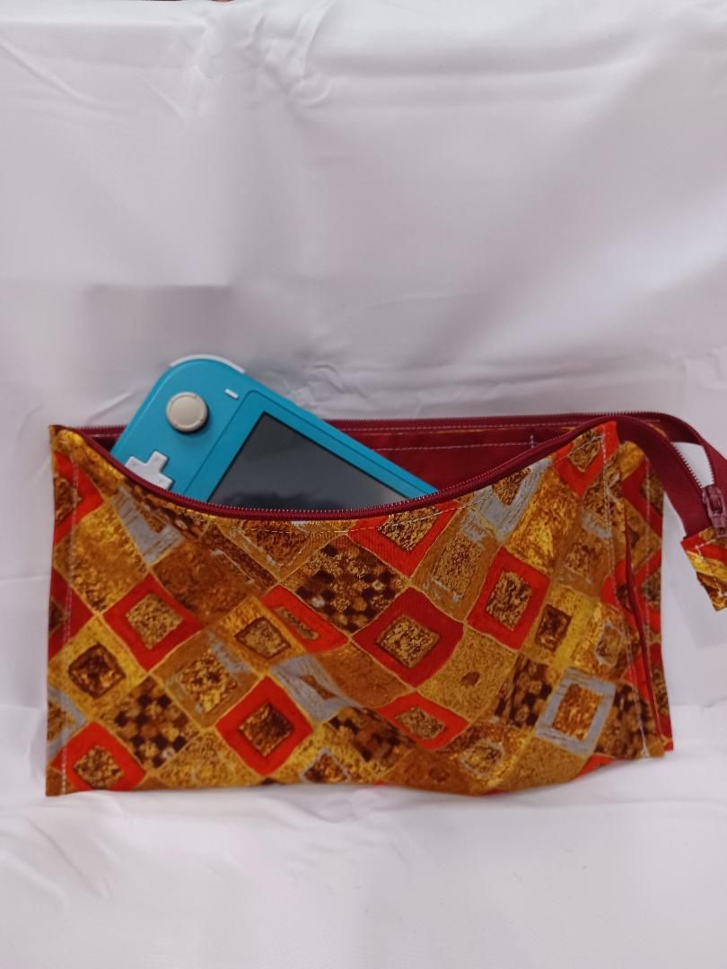 Patterned fabric pouch with a blue folding tool partially tucked inside against a white background