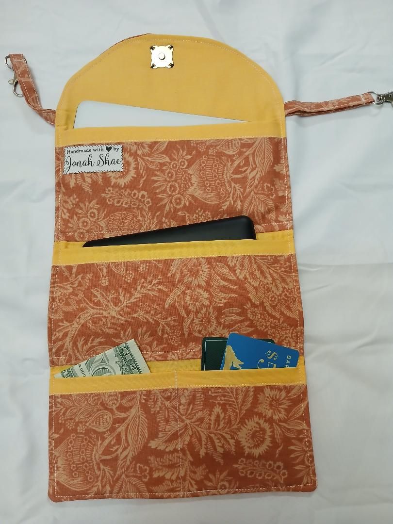 Orange patterned fabric organizer with pockets and a drawstring on top, hanging on a white background