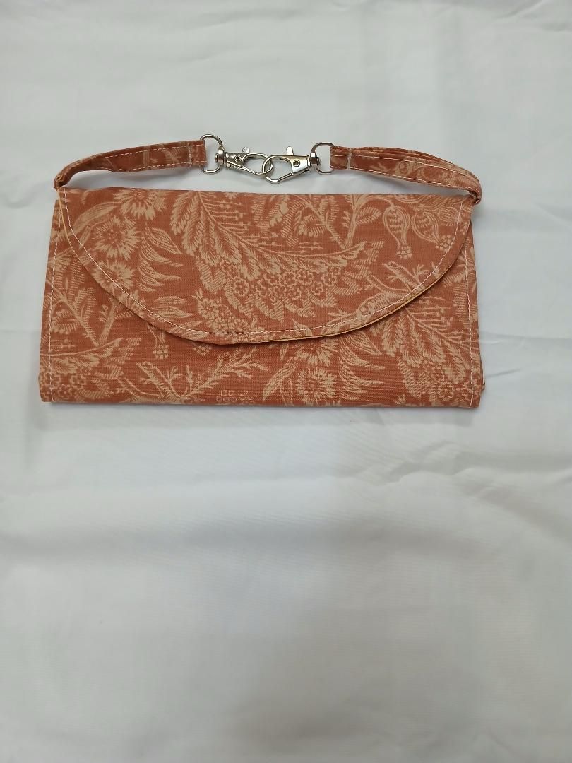 Orange patterned handbag with a flap and silver clasp on a light background