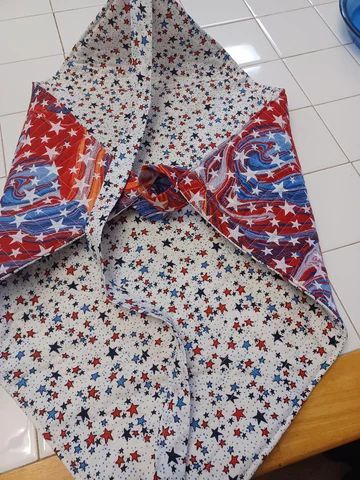 Patriotic star-patterned fabric with red, white, and blue accents, laid open on a tiled floor.