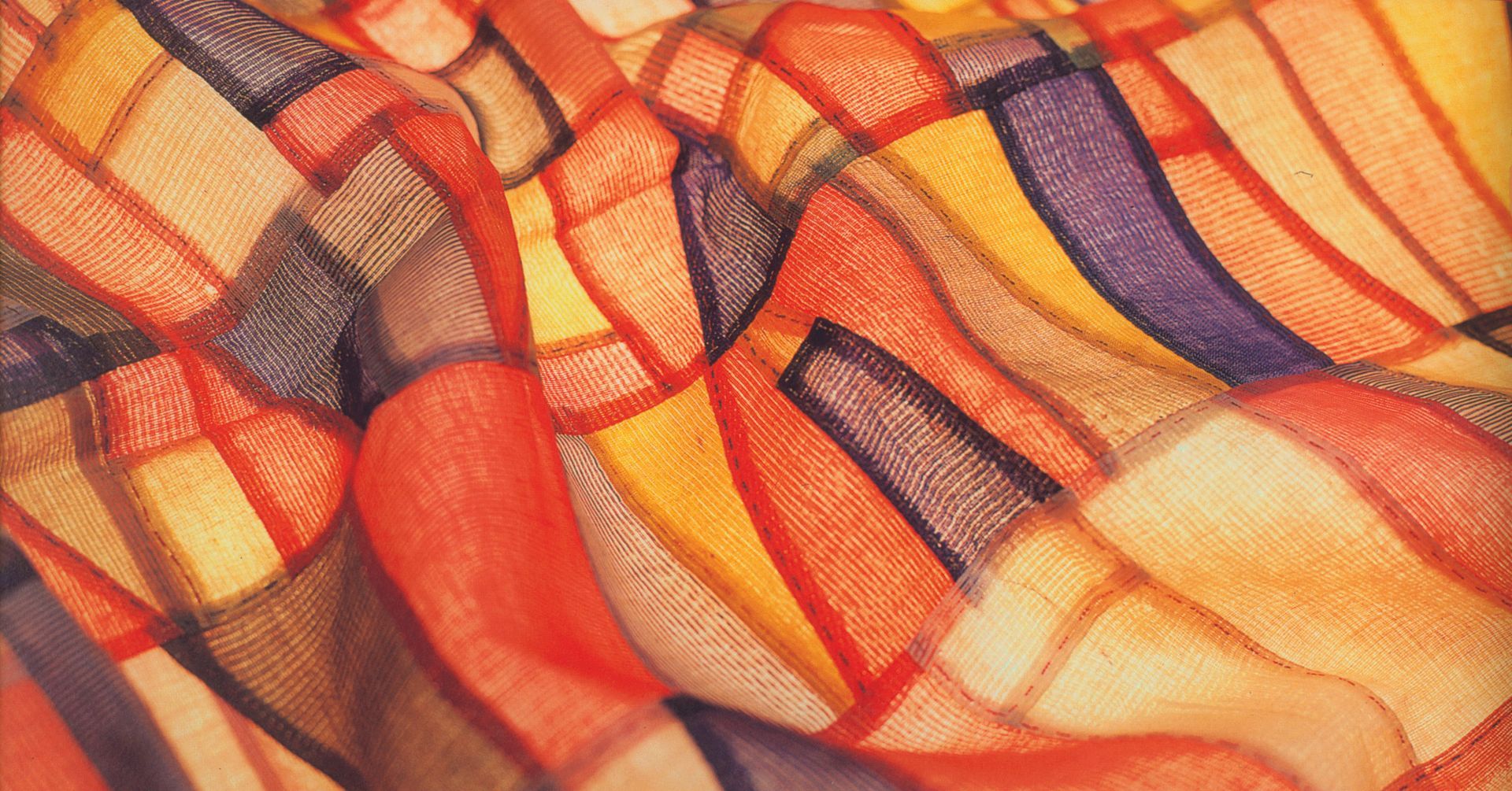 Abstract fabric texture with flowing orange, red, purple, and cream wavy stripes and plaid accents