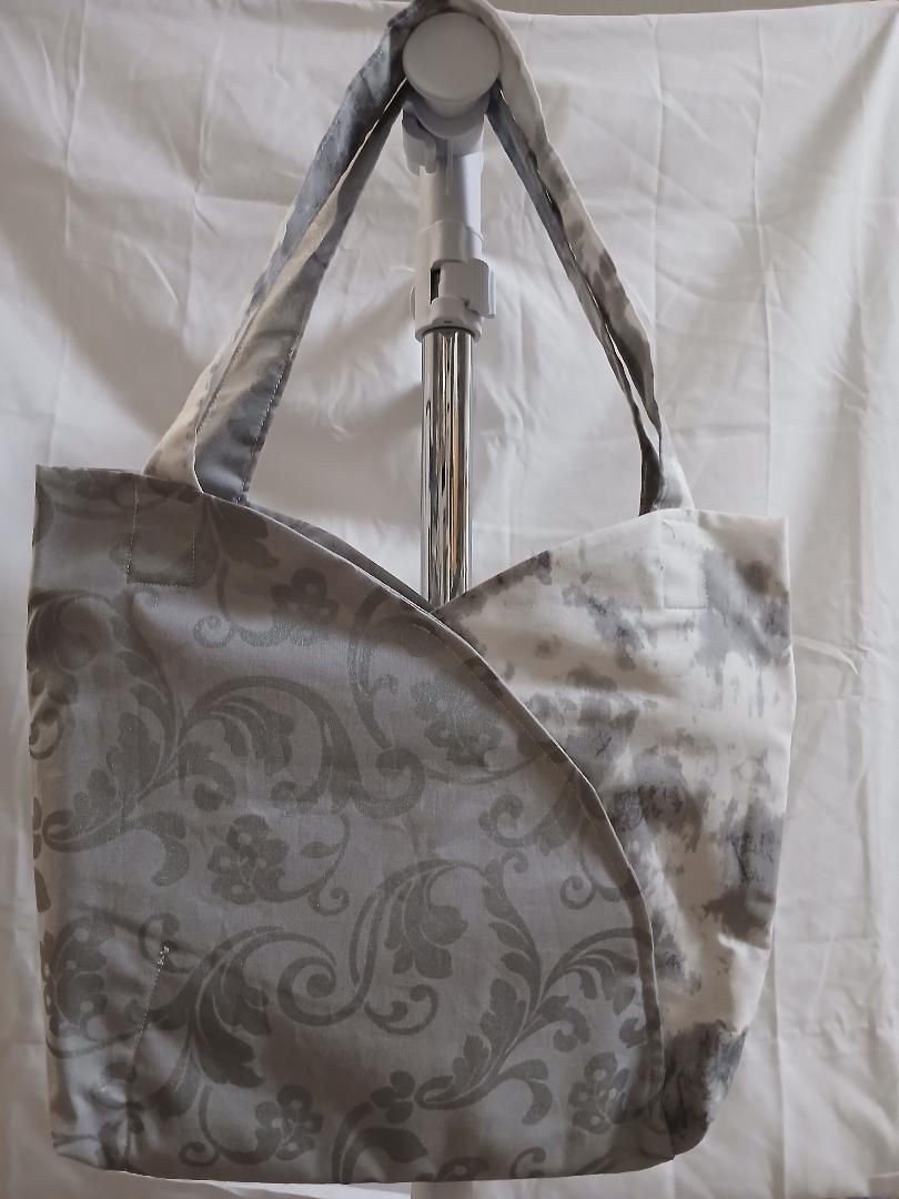 Gray floral handbag hanging on a hook against a white background