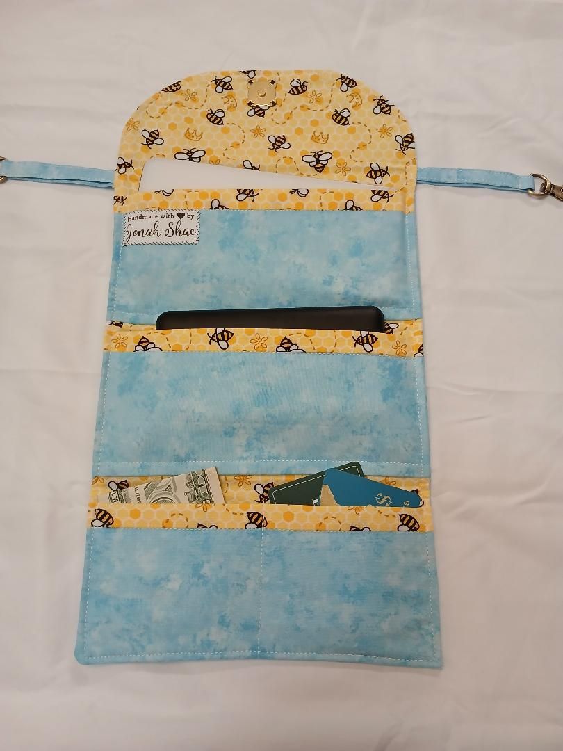 Blue-and-yellow fabric pouch with flap and ties, hanging against a light background