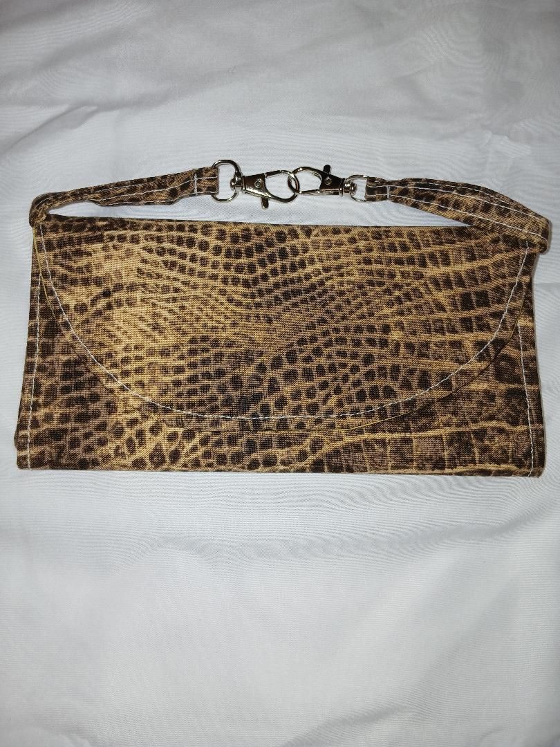 Brown snakeskin-pattern clutch purse with a chain strap on a white fabric background