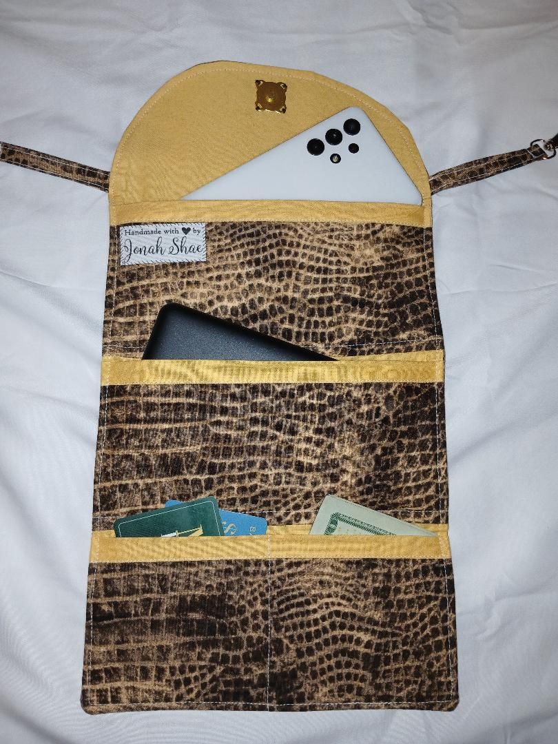 Brown patterned hanging wall organizer with yellow top and pockets holding small items