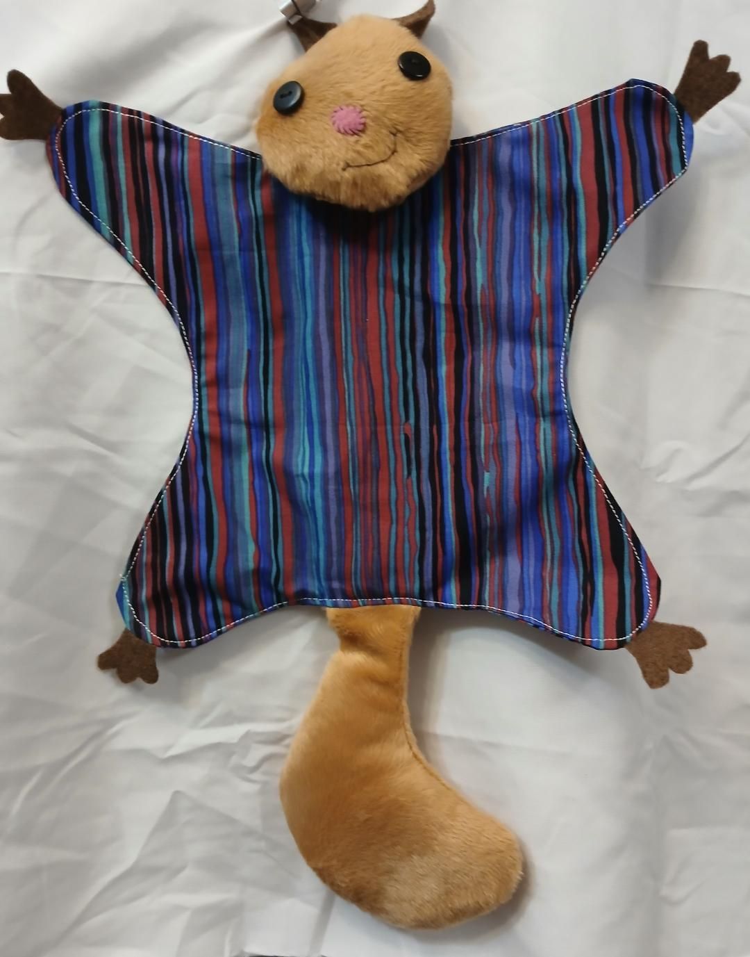 Plush cat toy with striped shirt and tail, lying on a white background with arms and legs spread.
