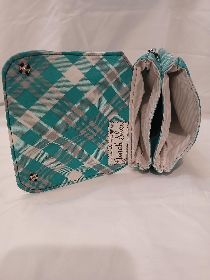 Small teal plaid zippered pouch with open beige lining, shown on a white background