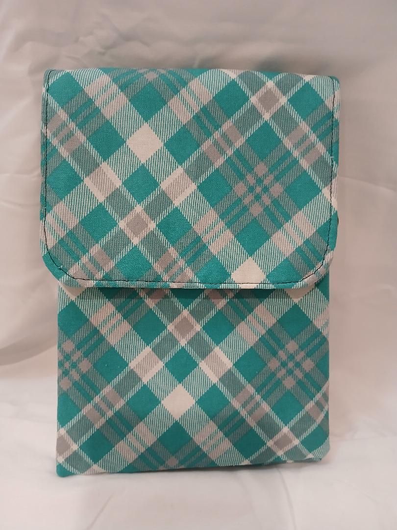 Two green plaid fabric pouches stacked on a beige surface