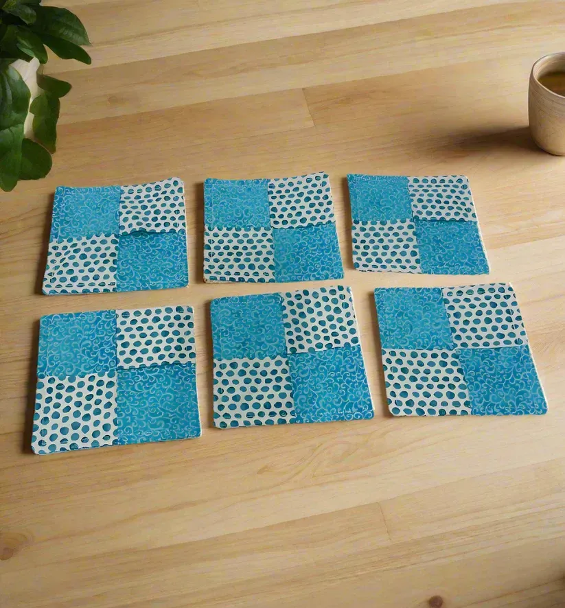 Six blue patterned fabric squares arranged in two rows on a wooden table.