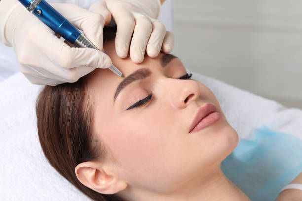 Woman having her eyebrow waxed; person's hand holds wax strip above eyebrow.