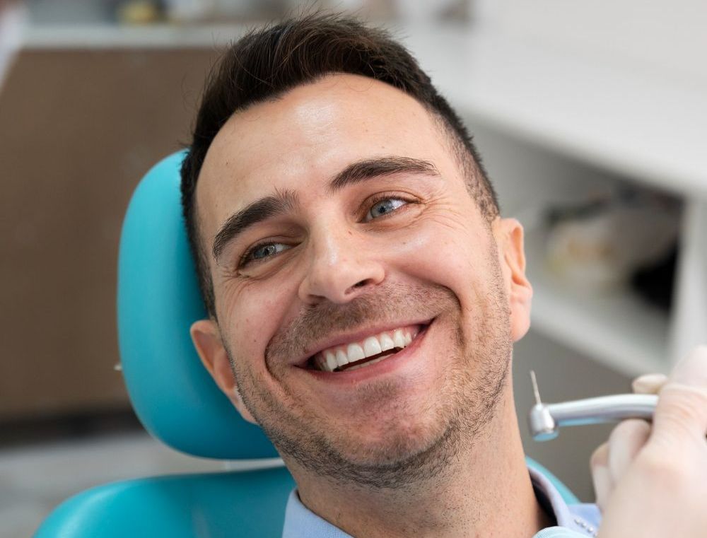 A man is smiling while sitting in a dental chair.