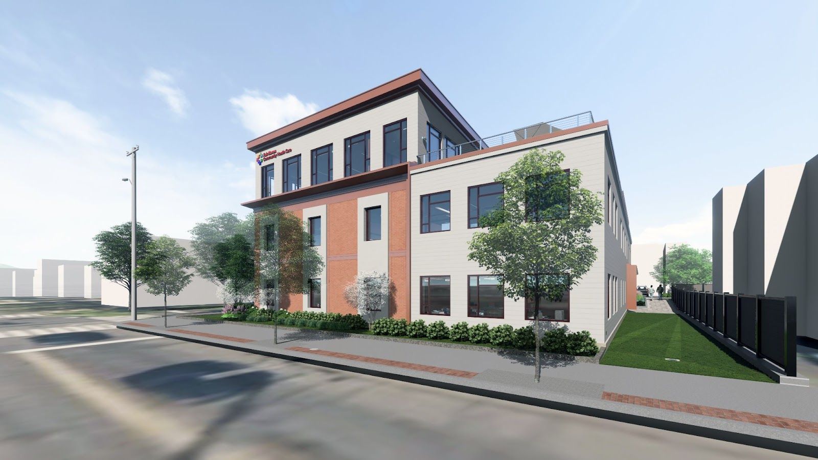 A three-story modern building with a mix of brick and light-colored siding, featuring large windows and street-level trees.