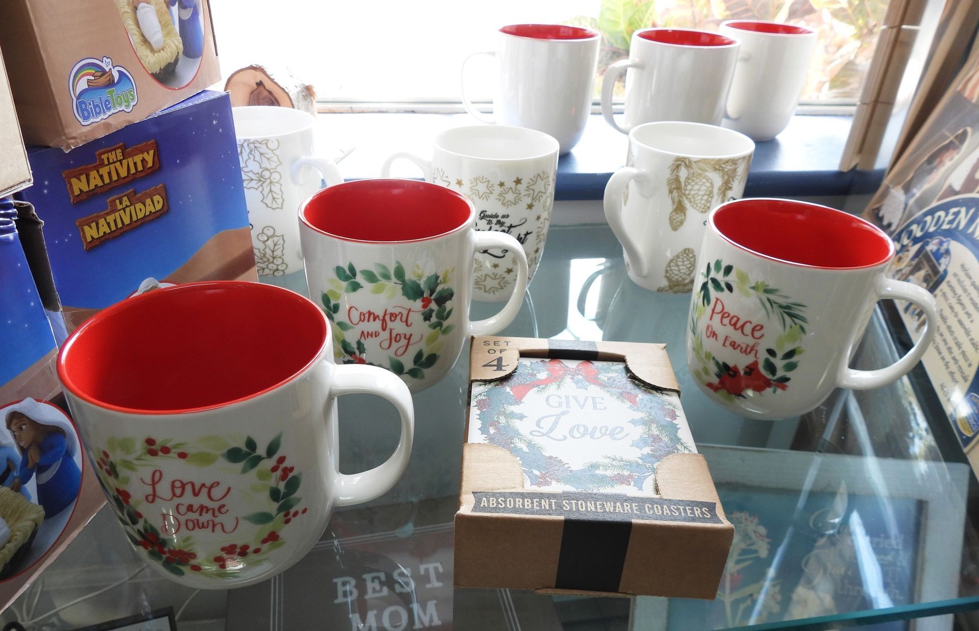 Mugs with red interiors and festive designs on display in a store.