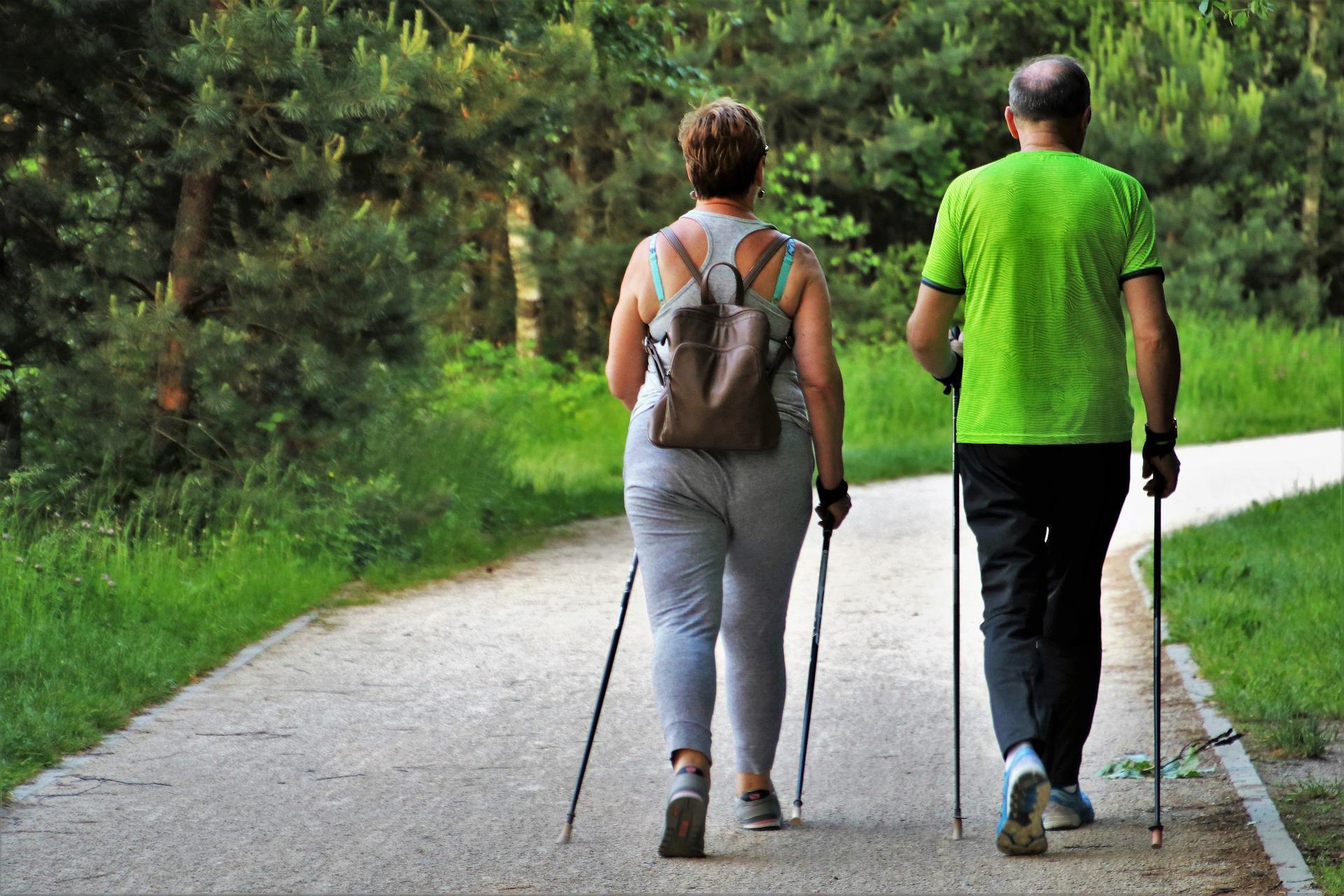woman and man using walking sticks on trail