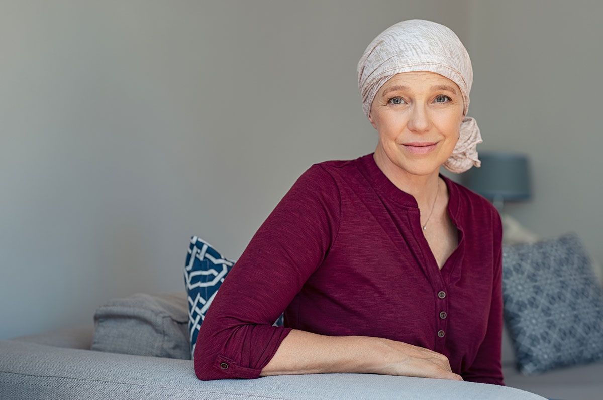 A Woman with Cancer Is Sitting on A Couch Wearing a Head Scarf — Marlton, NJ — Luna Lymphatic Care