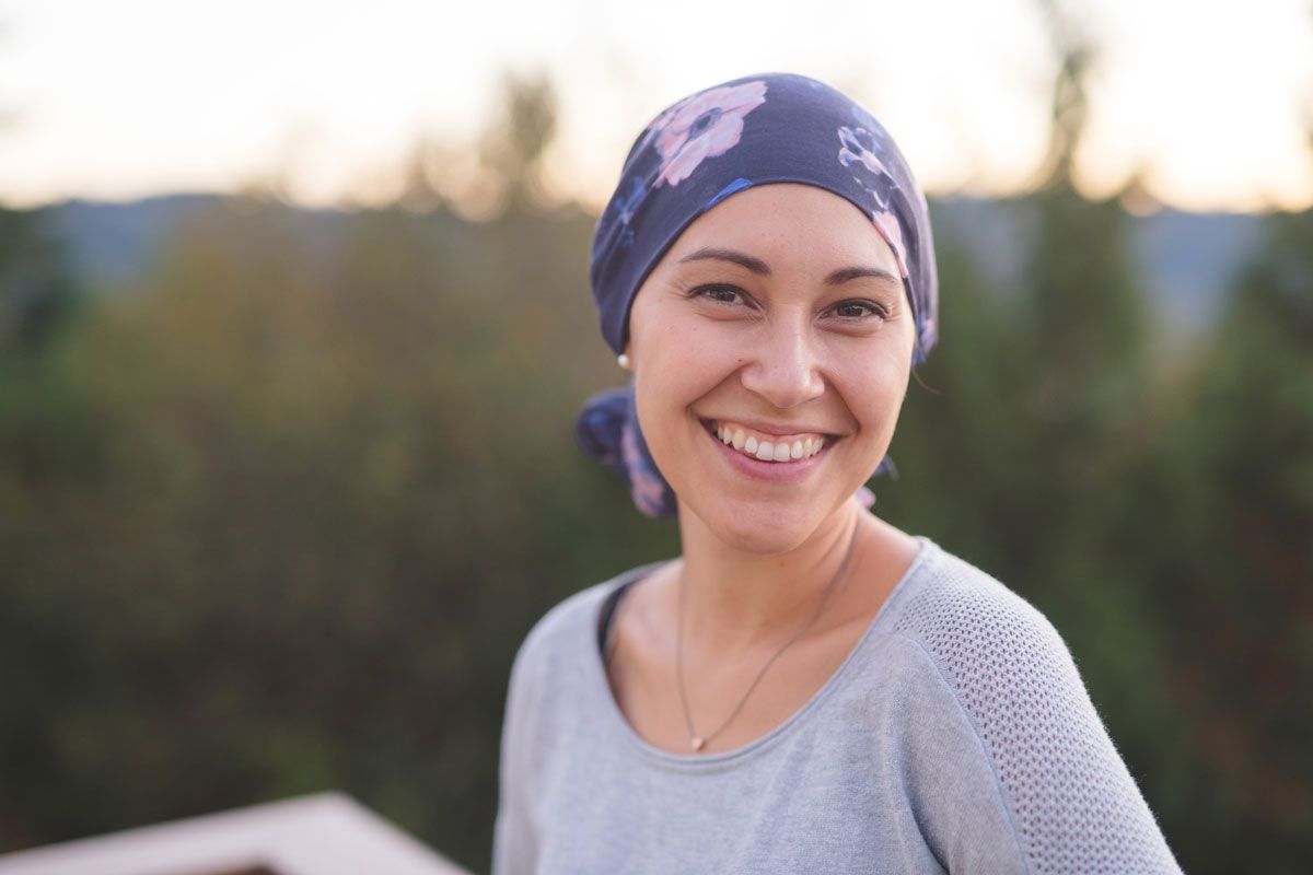A Woman with Cancer Is Wearing a Head Scarf and Smiling — Marlton, NJ — Luna Lymphatic Care