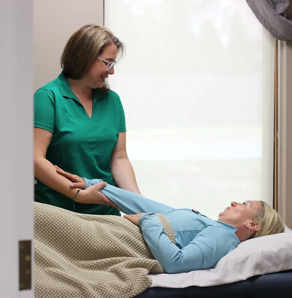 A Woman in A Green Shirt Is Talking to A Woman Laying on A Bed — Marlton, NJ — Luna Lymphatic Care