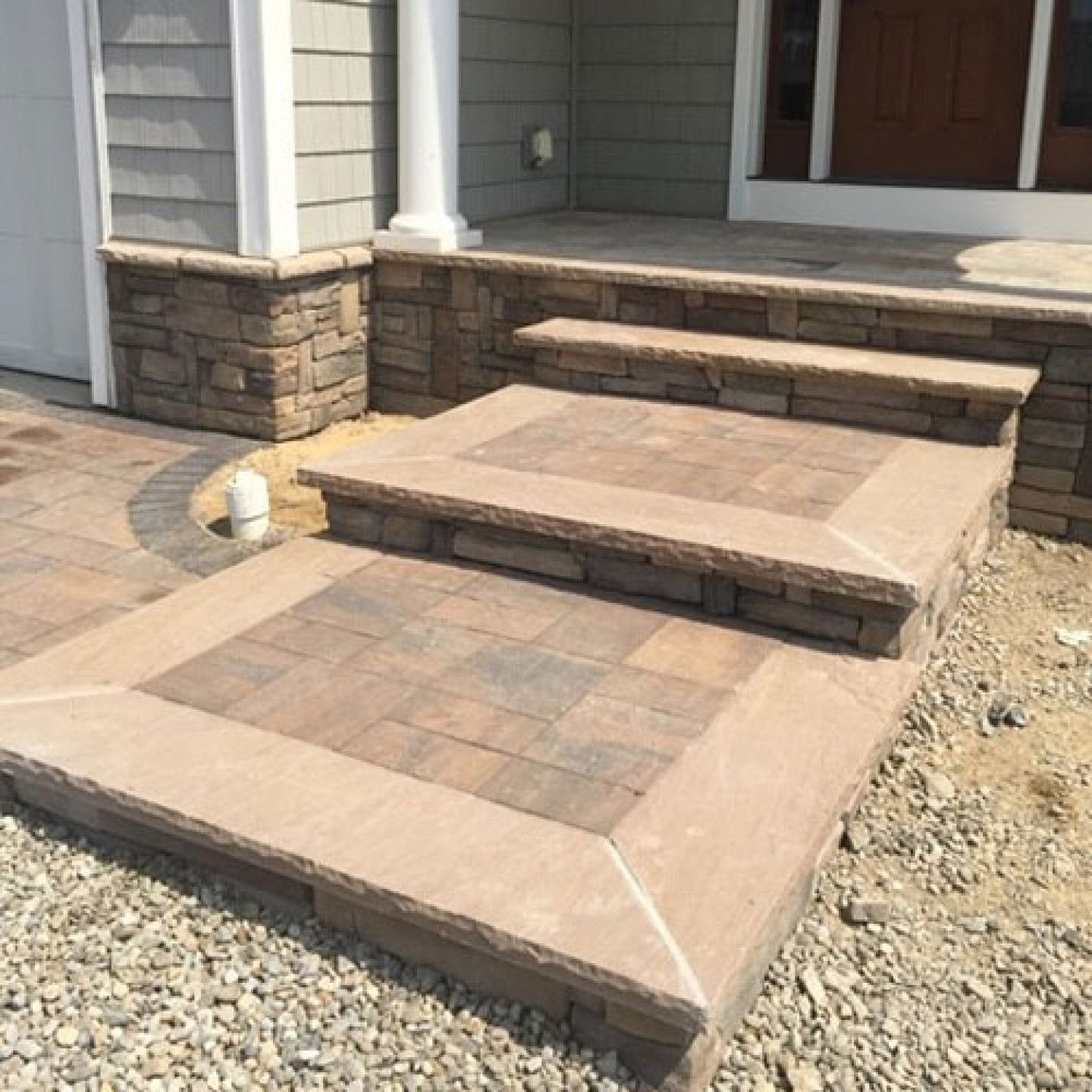 Stone steps leading to a house entrance. Light brown and gray stonework.