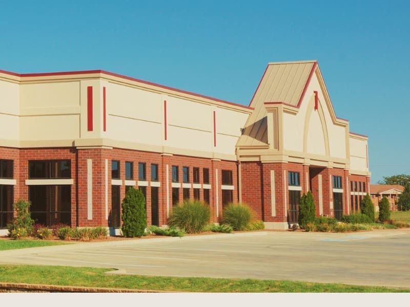 Commercial building with red brick facade, tan walls, and a blue sky.
