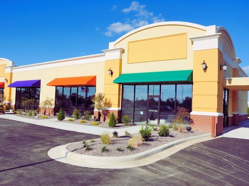 Commercial building with colorful awnings and large windows.