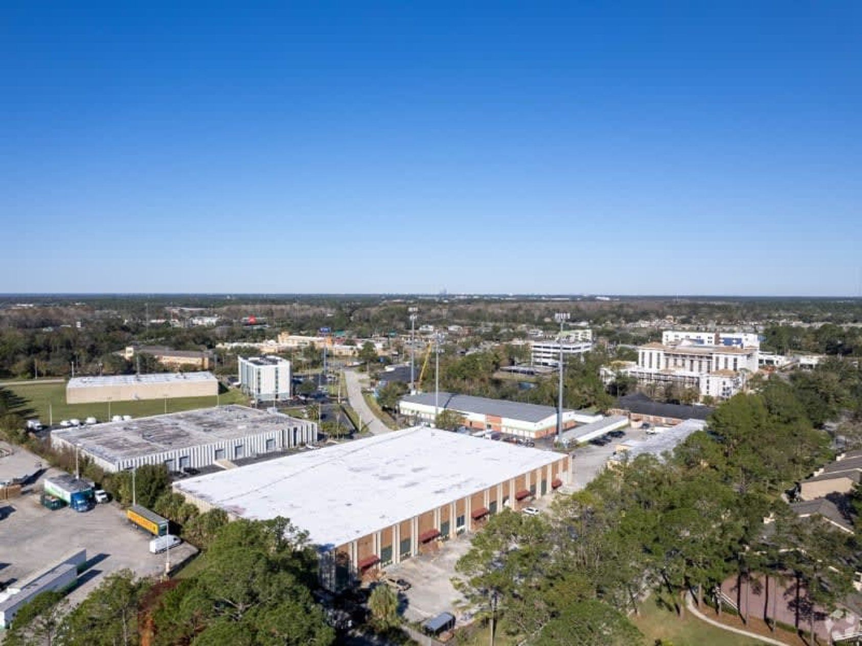 Aerial view of buildings and trees under a clear blue sky in an urban setting.