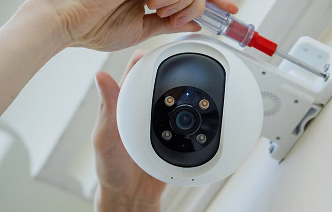 Person Installing a White Security Camera With a Screwdriver — NQ Video Surveillance in Bungalow, QLD