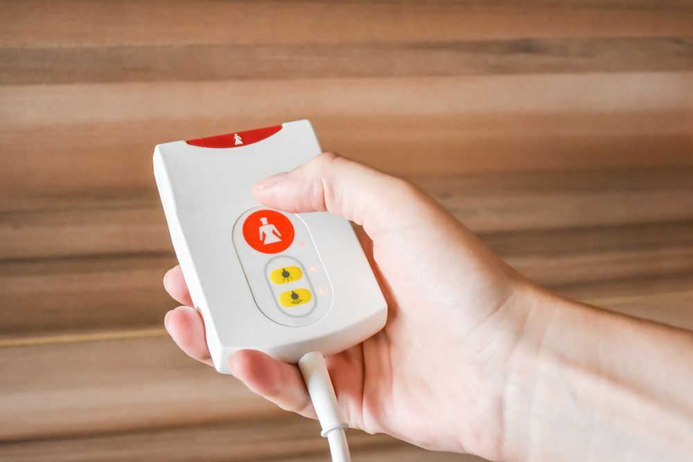 Hand Holding a White Alert Button With a Red and Yellow Buttons — NQ Video Surveillance in Bungalow, QLD