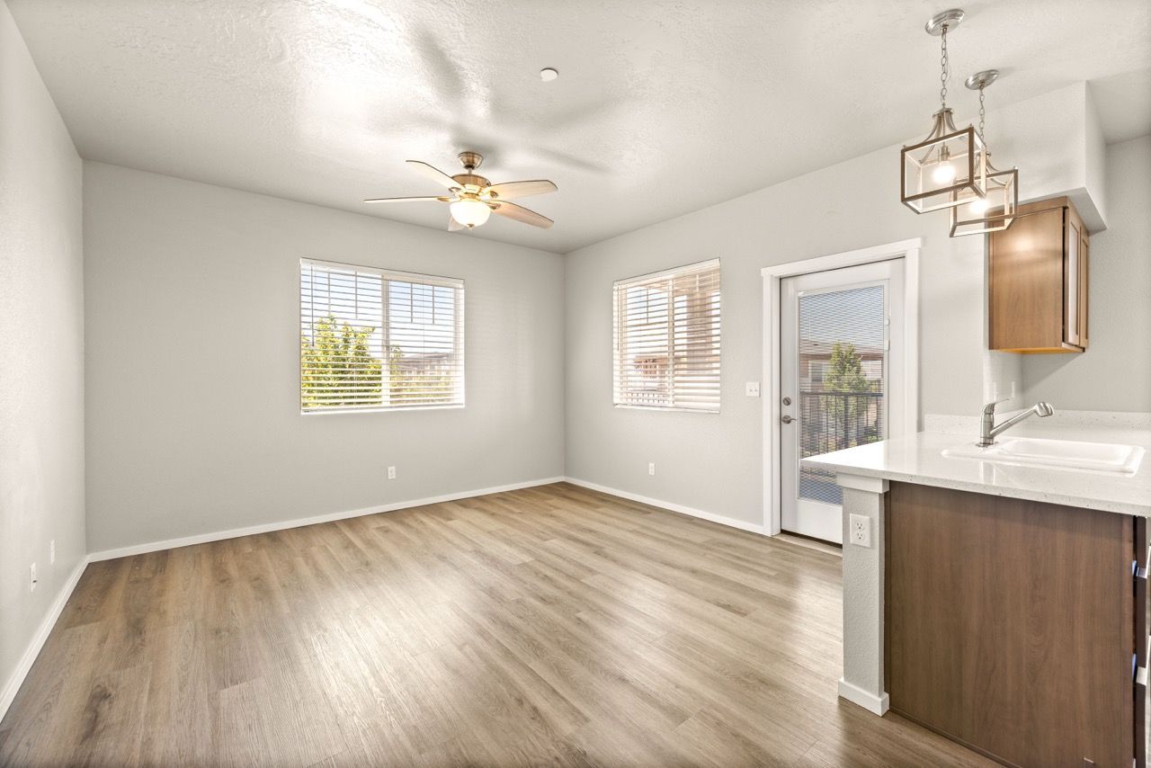 Bright living area with wood‑style flooring, two windows, and a kitchen counter with sink.