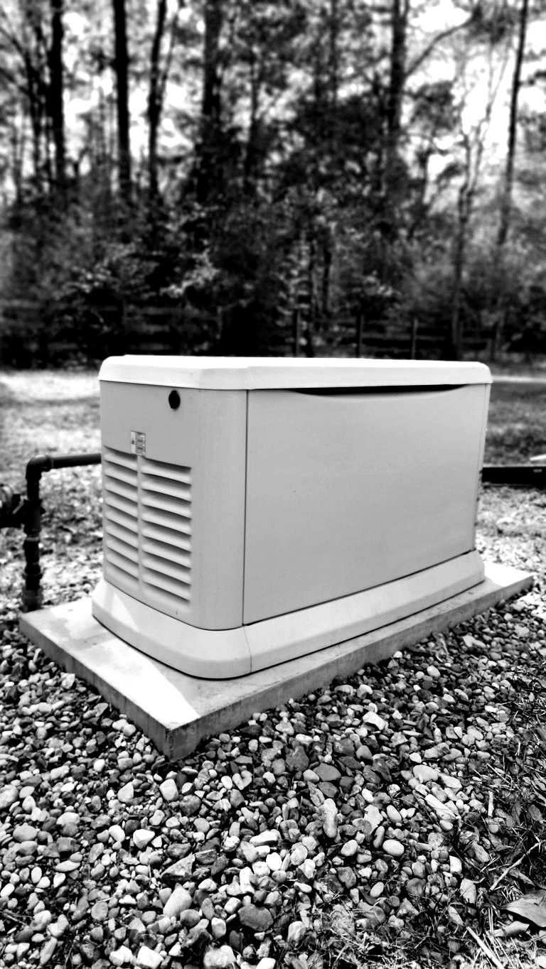 A black and white photo of a generator sitting on top of a pile of gravel.