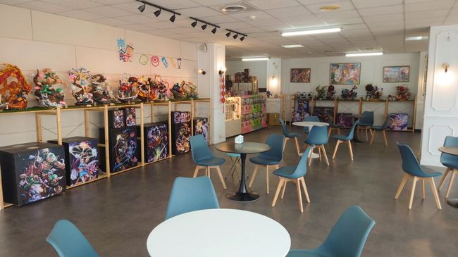 商店內部，貨架上擺放著動漫手辦和藝術品，並設有咖啡廳座位。