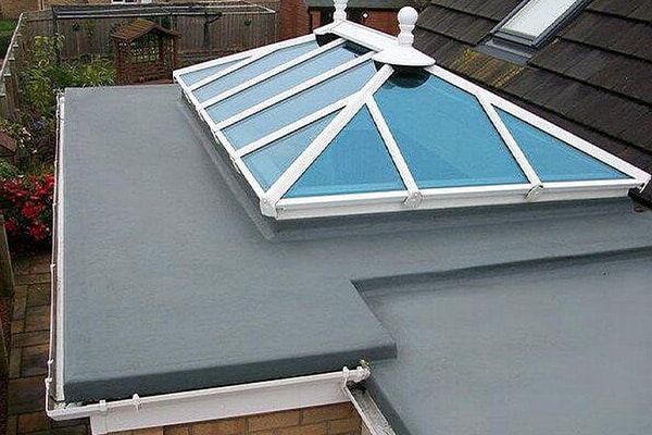 Flat gray roof with a blue glass skylight and white frame on a residential building