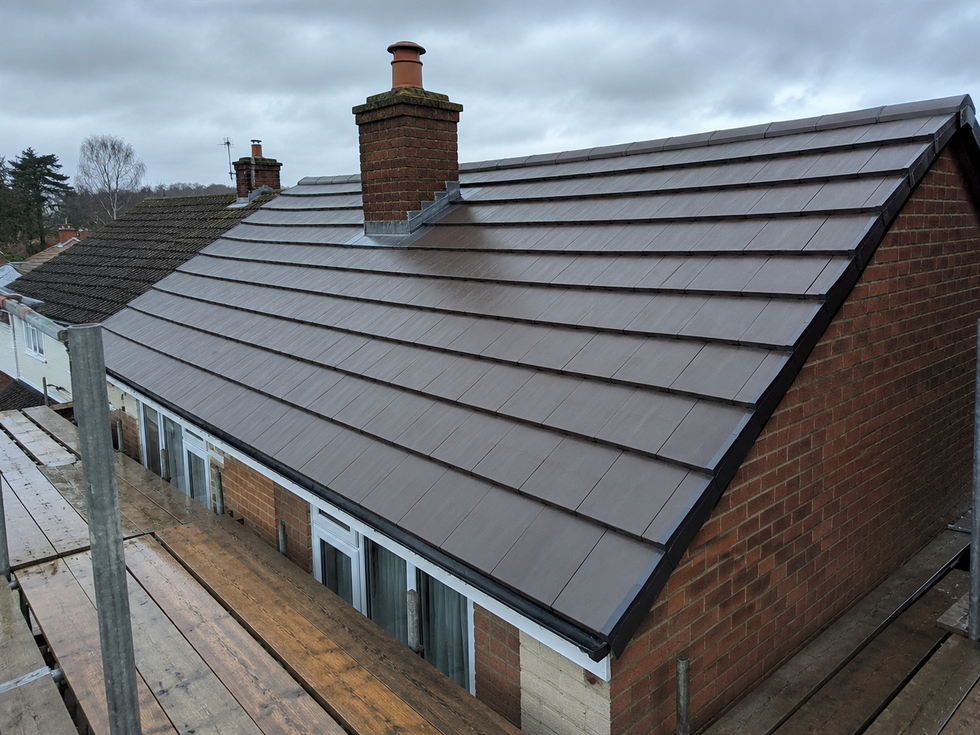 Slate roof on a brick house with two chimneys, viewed from above in a residential area.