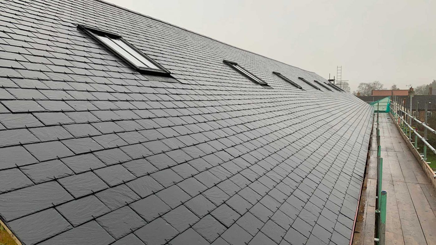 Slate roof with two skylights beside a rooftop walkway on an overcast day