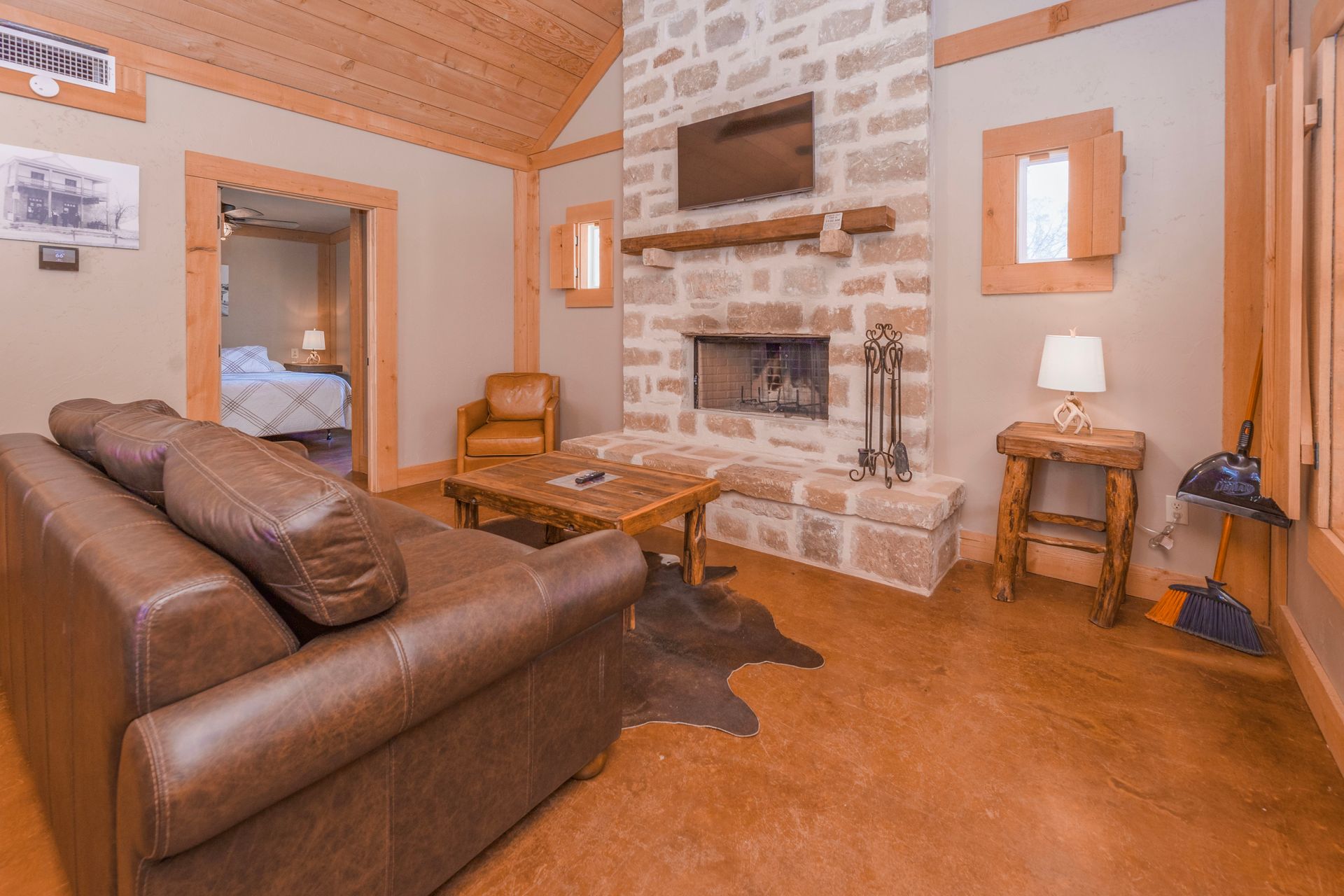 Cozy living room with stone fireplace, brown leather sofa, and wooden furniture.