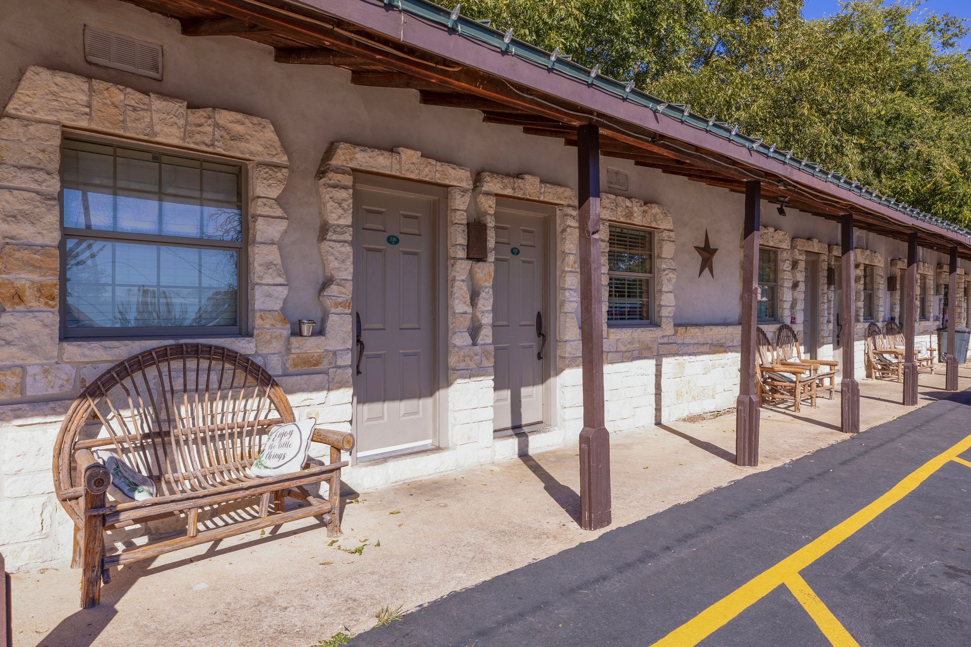 Motel exterior with stone facade, wooden porch, and a bench.