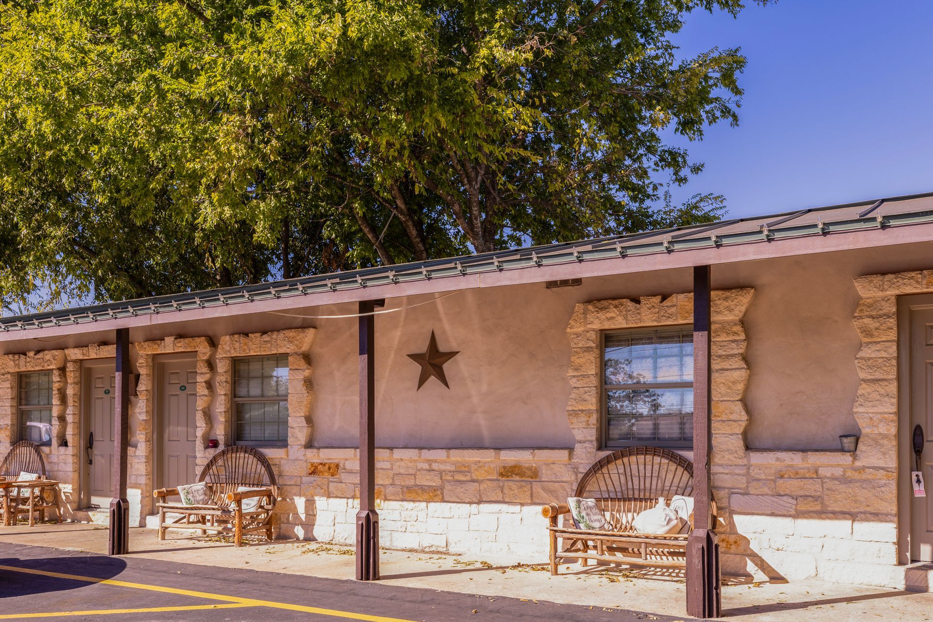 Exterior view of a motel with stone accents and a large star decoration; benches under a covered walkway.