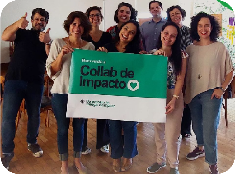 Um grupo de pessoas segurando uma faixa que diz collab de impacto
