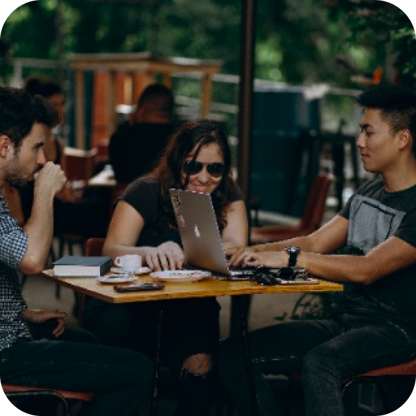 Um grupo de pessoas está sentado em uma mesa usando laptops